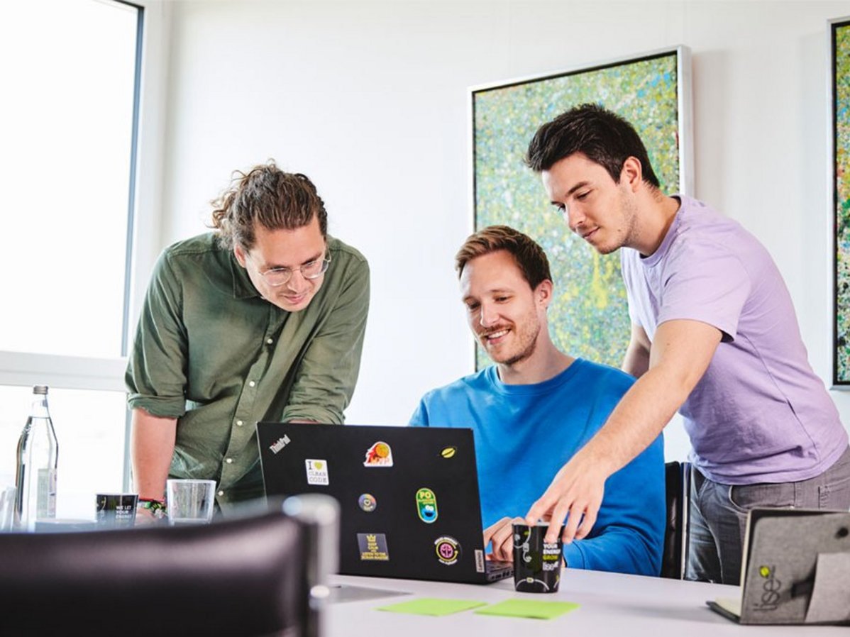Drei lise-Entwickler beraten sich gegenseitig vor einem Computer über den passenden Managed-Cloud-Service-Anbieter