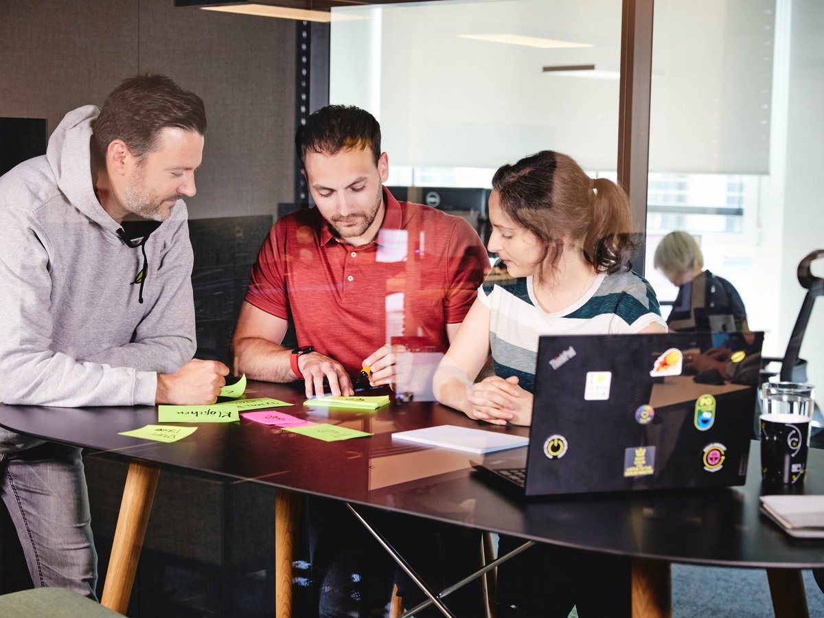 Ein kleines lise-Team arbeitet gemeinsam an einem Projekt und nutzt Post Its, sowie Stifte und Laptops