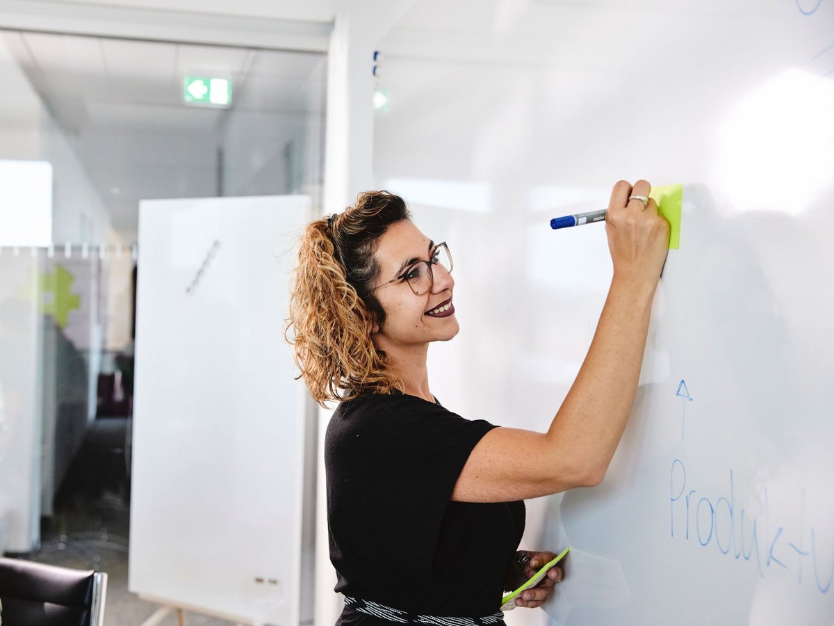 Eine lise-Entwicklerin notiert wichtig Erkenntnisse auf einem Whiteboard mit einem blauen Stift