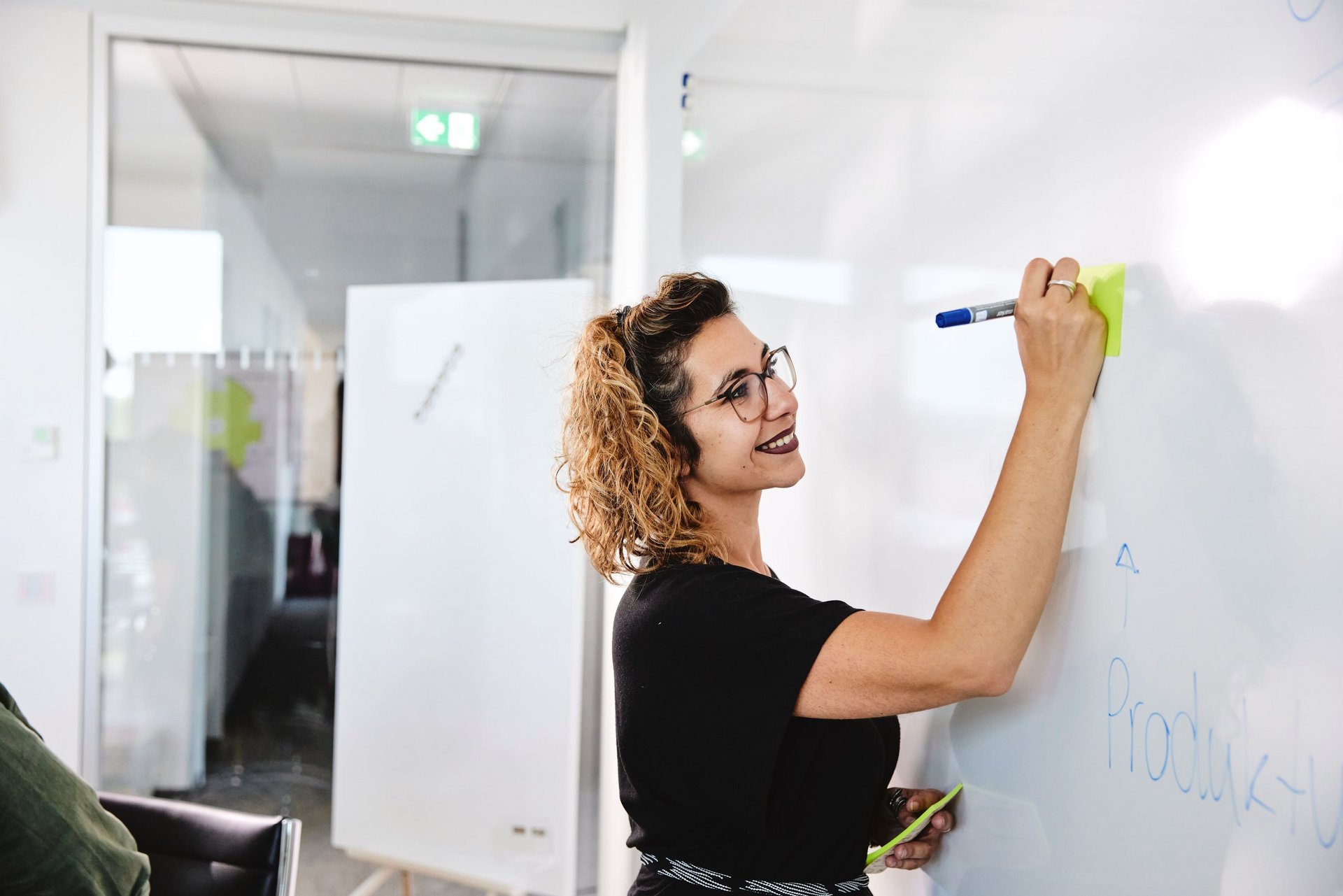 Eine lise-Entwicklerin macht Notizen auf einem Whiteboard mit einem blauen Stift