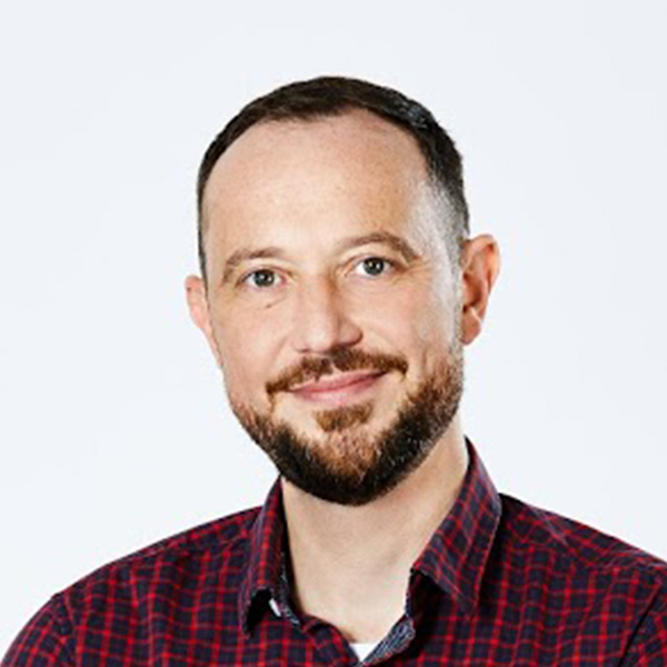 Portrait des Geschäftsführers Daniel Schwarz in einem rot-schwarz karierten Hemd vor einem weißen Hintergrund