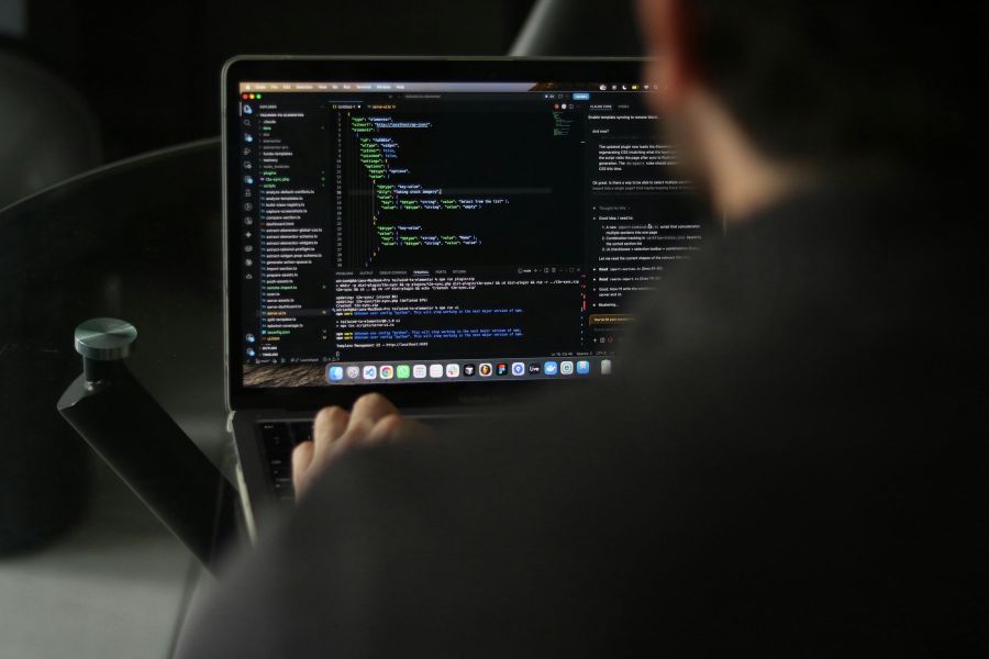 Blick auf den Code Man sieht einen Entwickler von hinter währenddessen dieser an seinem Computer programmiert