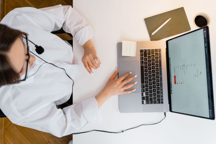 Kundenservice mit KI Eine Kundenberaterin sitzt an ihrem Computer und spricht über ein Headset.