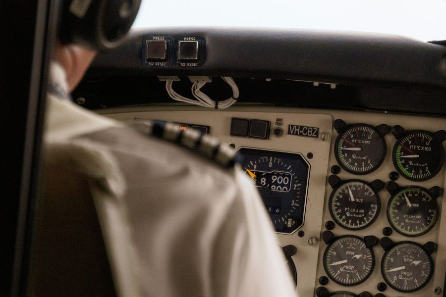 Man sieht einen Piloten von hinten und ein altes Cockpit vor ihm.