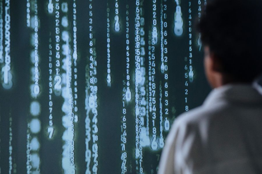 Ein Entwickler steht vor einem großen Bildschirm mit vielen Codes.