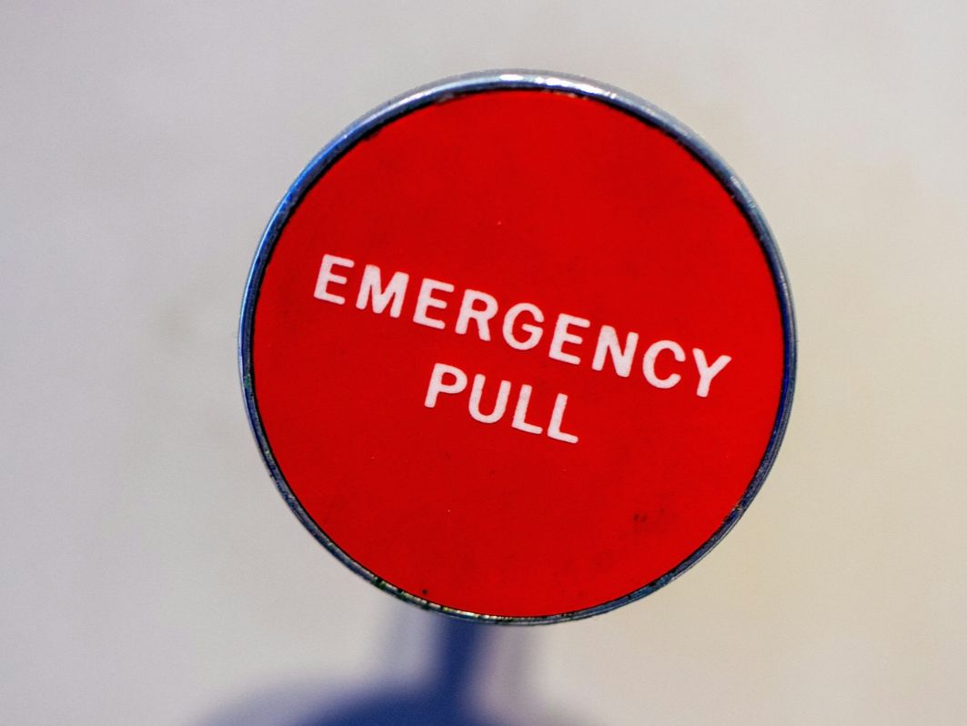 Auf einem hellen Hintergrund ist ein rotes Schild zu sehen, mit der Aufschrift "Emergency Pull"